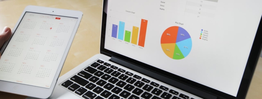 Laptop displaying charts and graphs with tablet calendar for data analysis and planning.